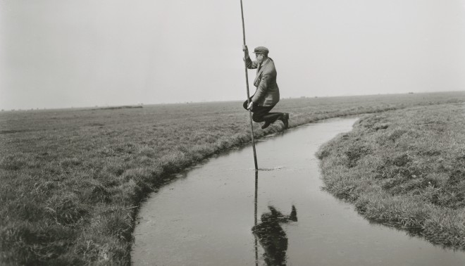 Man springt met een polsstok over de sloot met kievitseieren in zijn pet, 1952. Foto: Ben van Meerendonk/IISG
