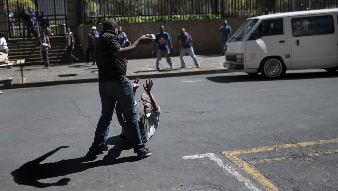 Een locale taxichauffeur valt een man van buitenlandse afkomst aan, tijdens rellen tegen buitenlanders in Johannesburg op 15 april jl. Foto: Marco Longari/AFP