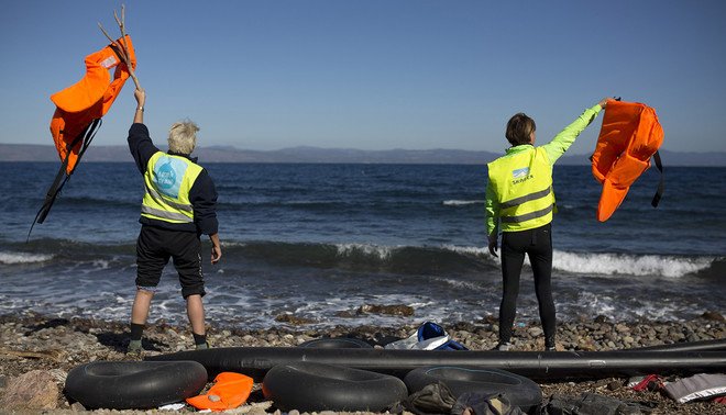 Lesbos, Griekenland (2 nov 2015). Vrijwilligers seinen vluchtelingen richting land. Foto: Hollandse Hoogte