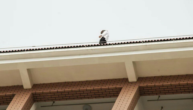 Op 23 april jl. verscheen een Chinese studente op het dak van de Beifang Universiteit in de Chinese stad Yunchuan. De reden dat ze zelfmoord wilde plegen zou te maken hebben met een slechte ontwikkeling in haar liefdesleven. Foto: Stringer / HH