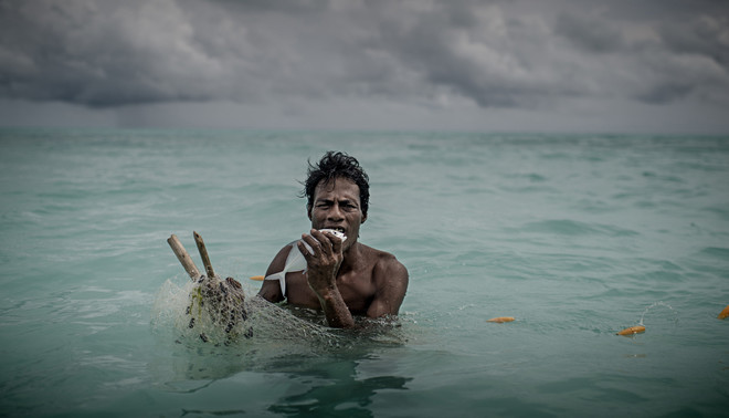 Een visser in Kiribati bijt een door hem gevangen vis dood. Kiribati heeft een gele kaart gekregen van de EU. Foto: Jonas Gratzer / LightRocket via Getty Images