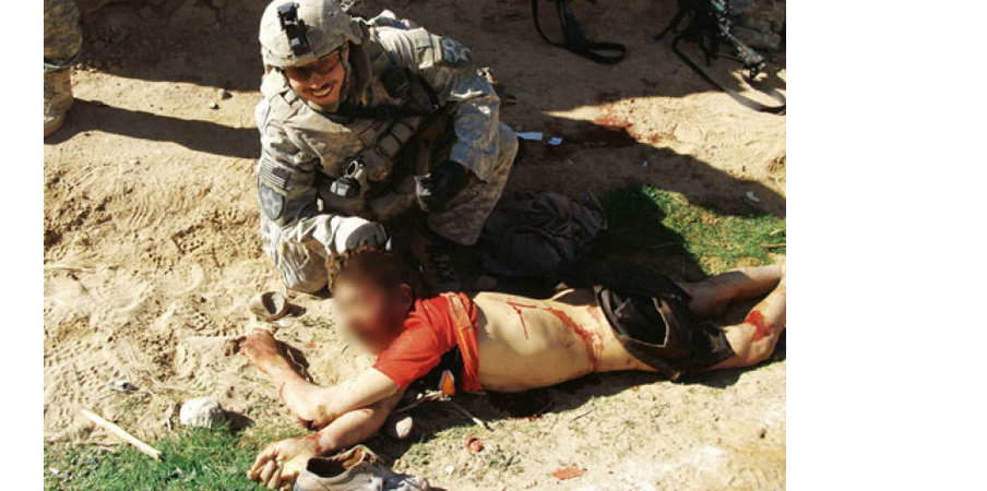 Een Amerikaanse soldaat poseerde in januari 2010 bij het lichaam van een Afghaanse jongen die een paar minuten daarvoor is neergeschoten. 