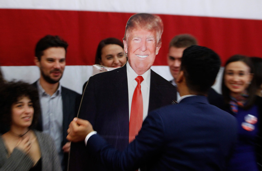 Een man draagt een uit karton gesneden Donald Trump tijdens een evenement op de Amerikaanse ambassade in Macedonië op de verkiezingsdag. Foto: Boris Grdanoski / AP