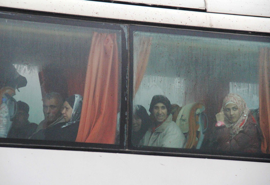 Syriërs zitten aan boord van een bus die vanuit Fuaa en Kafraya mensen naar Rashidin evacueert op 14 april, 2017. Foto: Omar Haj Kadour / AFP / ANP