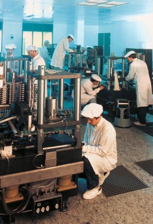 Foto boven: ASML’s eerste kantoor (het ‘houten noodgebouwtje’). Foto midden: ASML’s eerste chipmachine, de PAS2000. Foto onder: Assemblage van machines in de ‘cleanroom’. Foto’s: ASML.