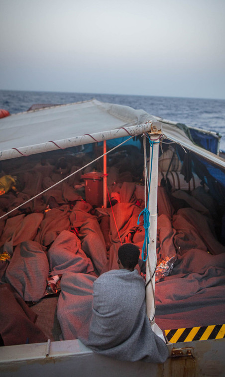 Een van de migranten zit op het dek, waar zij slapen, 6 juni 2018. Foto: Erik Marquardt